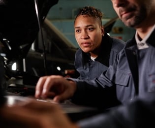 Students looking under the hood of an automobile