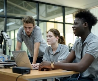 Students using a computer and small robotic arm