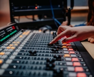 Soundboard in a music studio being operating by a hand
