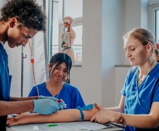 Students in lab coats practicing taking blood