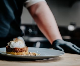 Student in a kitchen standing behind a fancy dessert