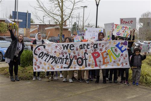 Faubion and Concordia community members lead the Peach March with a large banner that reads "We are a community of Peace" 