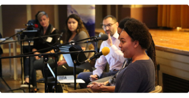 A photo of students speaing into a microphone