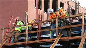 workers pouring concrete for wall of new gym 