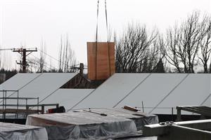 Crane lifts Mass timber panel into building through roof 