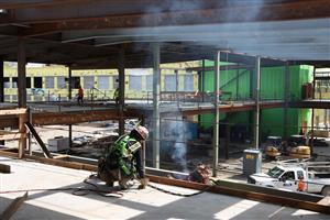 Workers welding with framing of walkway behind