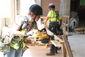 Female construction worker saws wood
