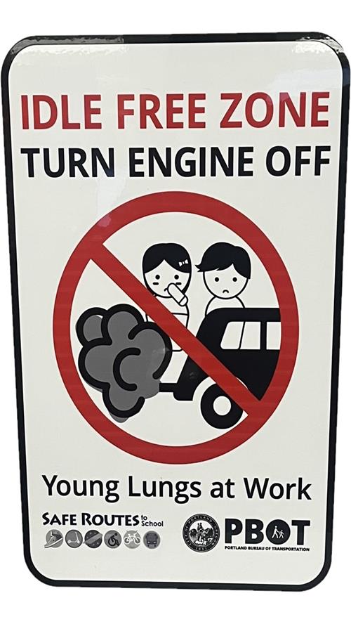 An idle free zone sign with two children breathing in car exhaust fumes with a "No" symbol transposed over the image. 